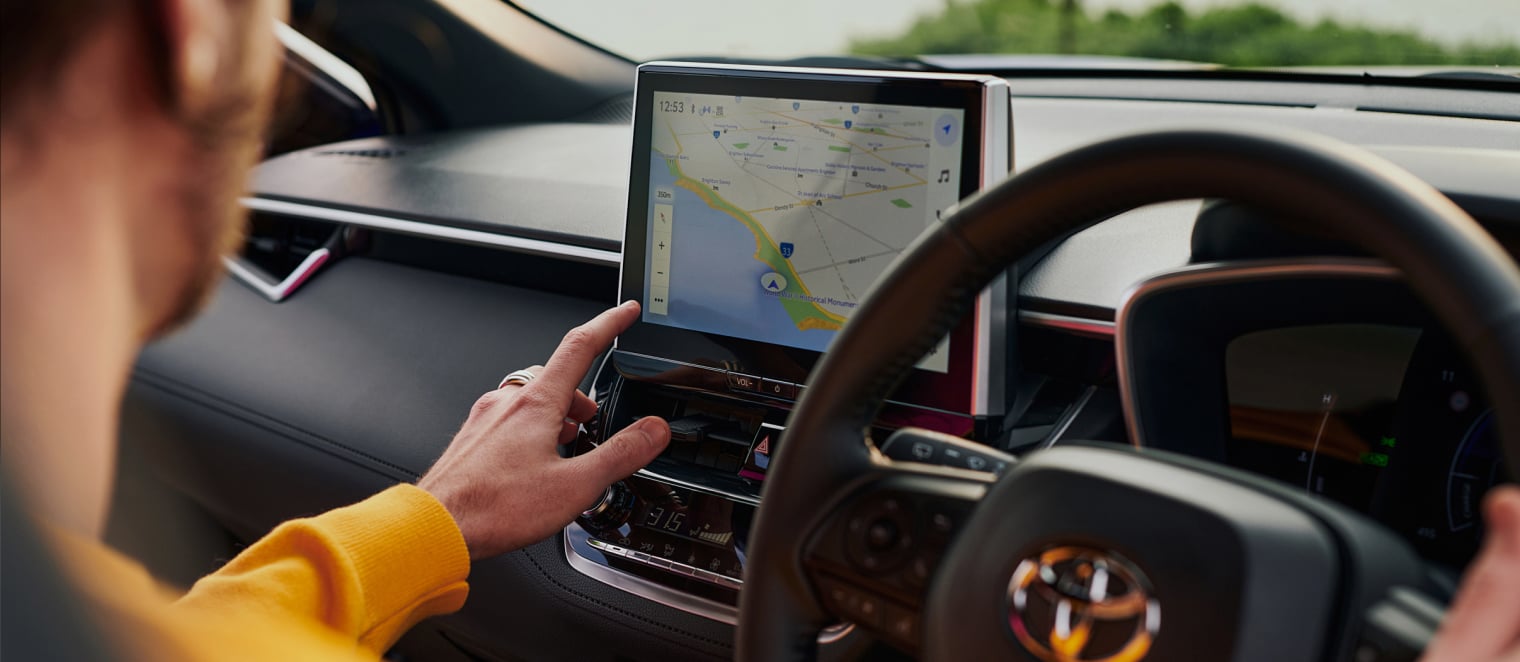 A man operating the multimedia unit inside his Toyota passenger car.